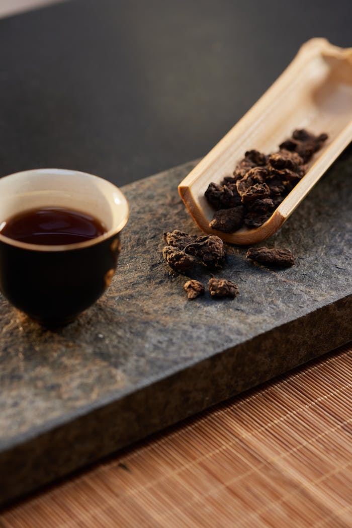 Artistic display of gourmet tea with bamboo scoop on slate and bamboo mat.